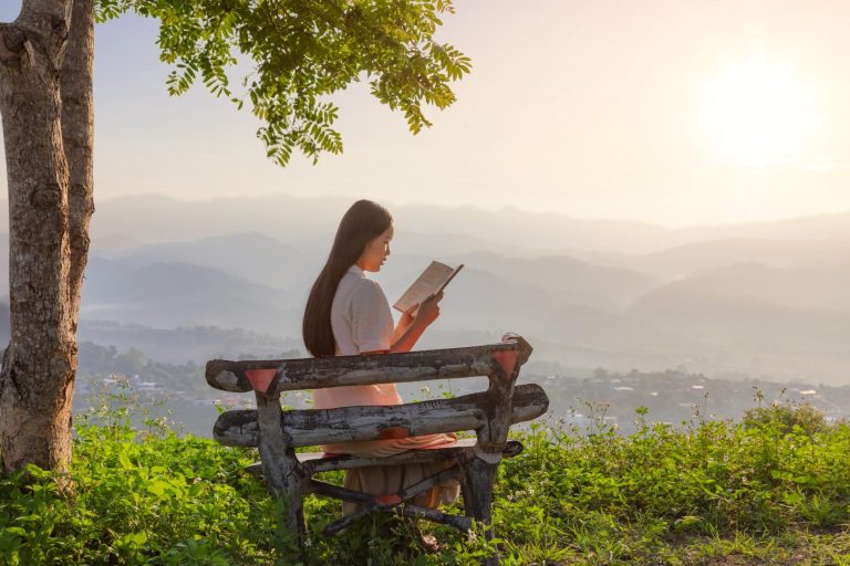 Woman reading a book on a bench - a Double Literacy sponsorship.